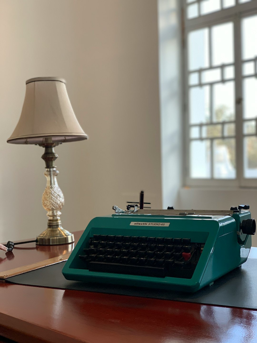 Vintage wooden writing desk with typewriter, notebook and dim lamp